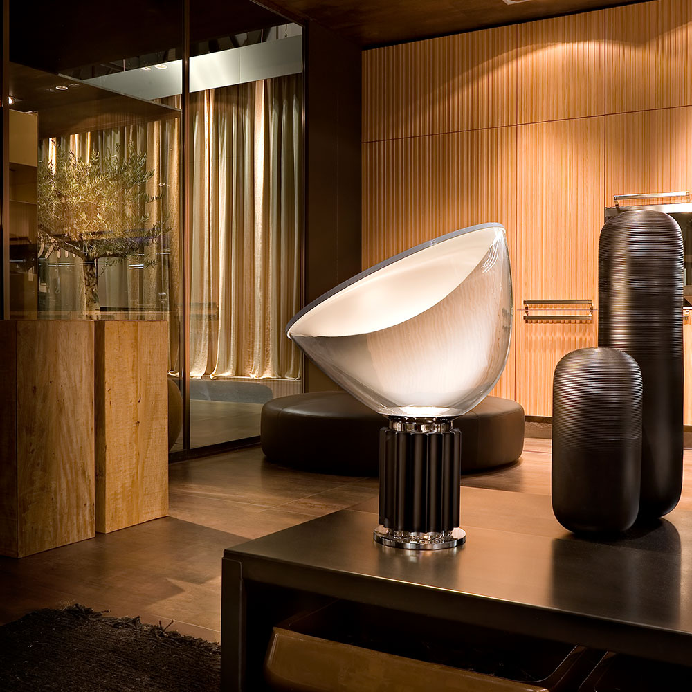 Die FLOS Taccia LED Tischleuchte bei lampenonline.de Ein Reflektor mit mattweißer Innenseite und glänzend weißer Außenseite liegt über dem Glasschirm und sorgt für eine nach unten gerichtete Lichtabstrahlung. 